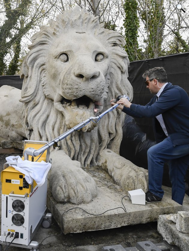 Szemerey-Kiss Balázs restaurátor lézeres technológiával tisztítja a Lánchíd budai hídfőjén álló oroszlánok egyikét, 2022 (Fotó: MTI/Kovács Tamás)