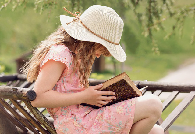 Otthon a kertben olvas egy lány a padon ülve (Fotó: Pixabay)