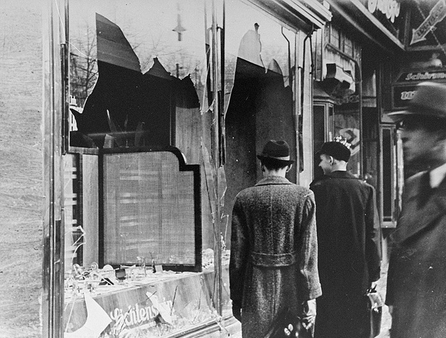 A nácik által zsidó üzletek betört ablakai előtt német állampolgárok mennek el. - Kristallnacht (kristályéjszaka),, 1938. november 10. (Fotó: Vertrieb az Associated Press (AP) és a Nemzetközi Hírszolgálat (INP)/PD at National Archives and Records Administration/Wikimedia)