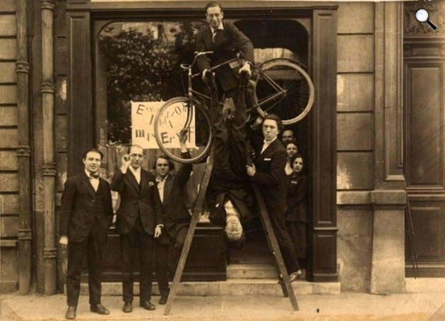 Max Ernst kiállítása - René Hilsum, Benjamin Péret, Serge Charchoune, Philippe Soupault on top of the ladder with a bicycle under his arm, Jacques Rigaut (upside down), André Breton and Simone Kahn, 1921(Fotó: Wikimedia/dadart.com)