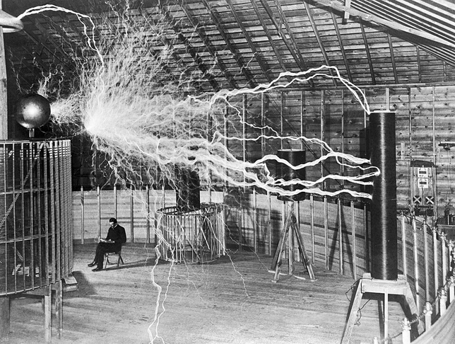 Nikola Tesla (1856-1943) fizikus, feltaláló, Colorado Springs -i laboratóriumában, amikor állítólag a Tesla-tekercs nagyfeszültségű generátora mellett ülve olvasott a hatalmas elektromos kisülés közben, 1899 (Fotó: Wikimedia/Dickenson V. Alley)